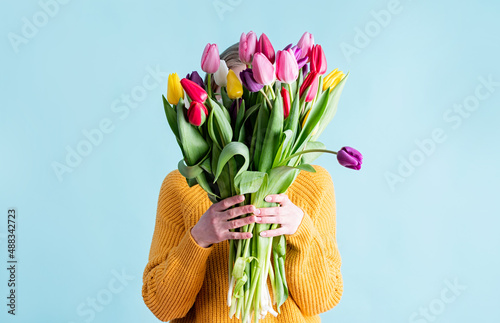 pretty charming young woman dressed yellow clothes holding tulip bunch isolated blue color background photo