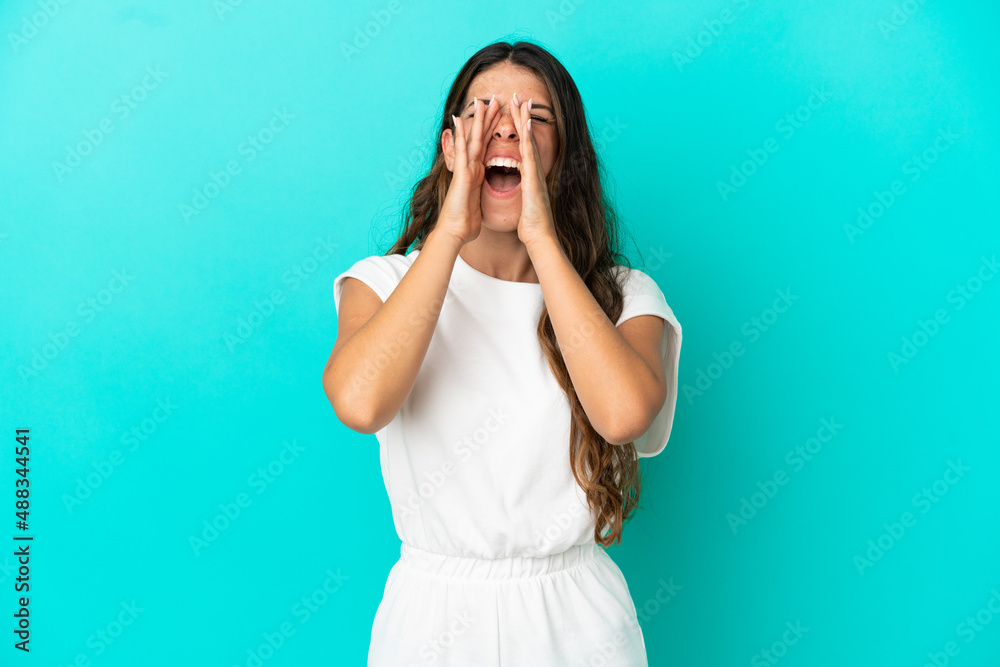 Young caucasian woman isolated on blue background shouting and announcing something Young caucasian woman isolated on blue background shouting and announcing something