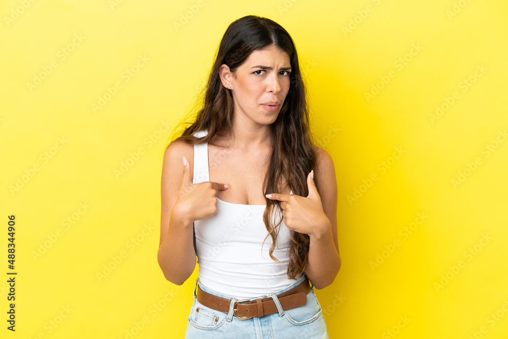 Young caucasian woman isolated on yellow background pointing to oneself