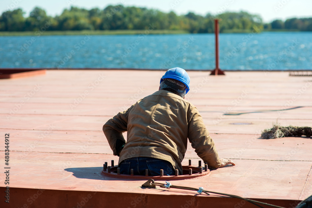 A sailor in a helmet climbs into the hold of the ship on the deck A sailor in a helmet climbs into the hold of the ship on the deck