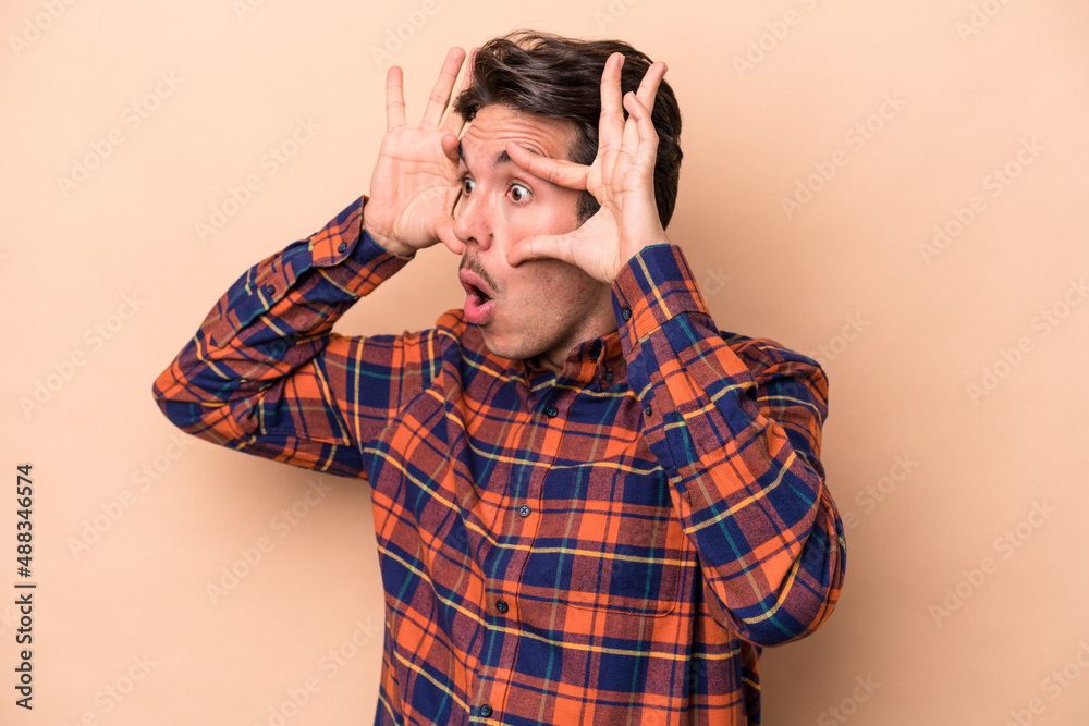Young caucasian man isolated on beige background keeping eyes opened to find a success opportunity. Young caucasian man isolated on beige background keeping eyes opened to find a success opportunity.
