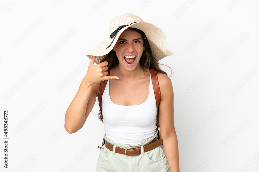 Young caucasian woman wearing a Pamela in summer holidays isolated on white background making phone gesture. Call me back sign Young caucasian woman wearing a Pamela in summer holidays isolated on white background making phone gesture. Call me back sign
