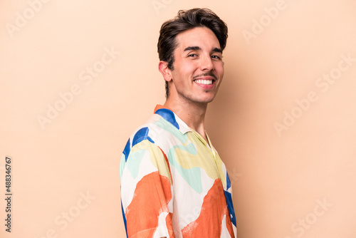 Young caucasian man isolated on beige background confident keeping hands on hips.