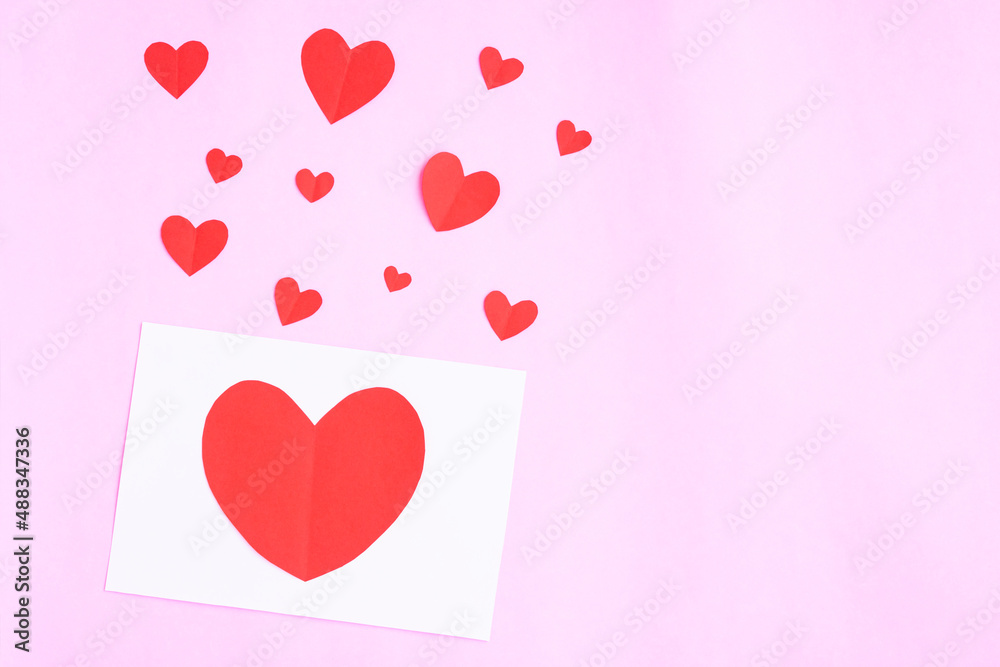 White greeting card with heart papercut on pink background