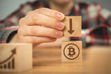 Concept of bitcoin decrease, arrow down. BTC graph of the growth symbols on a wooden cubes in hands close-up view