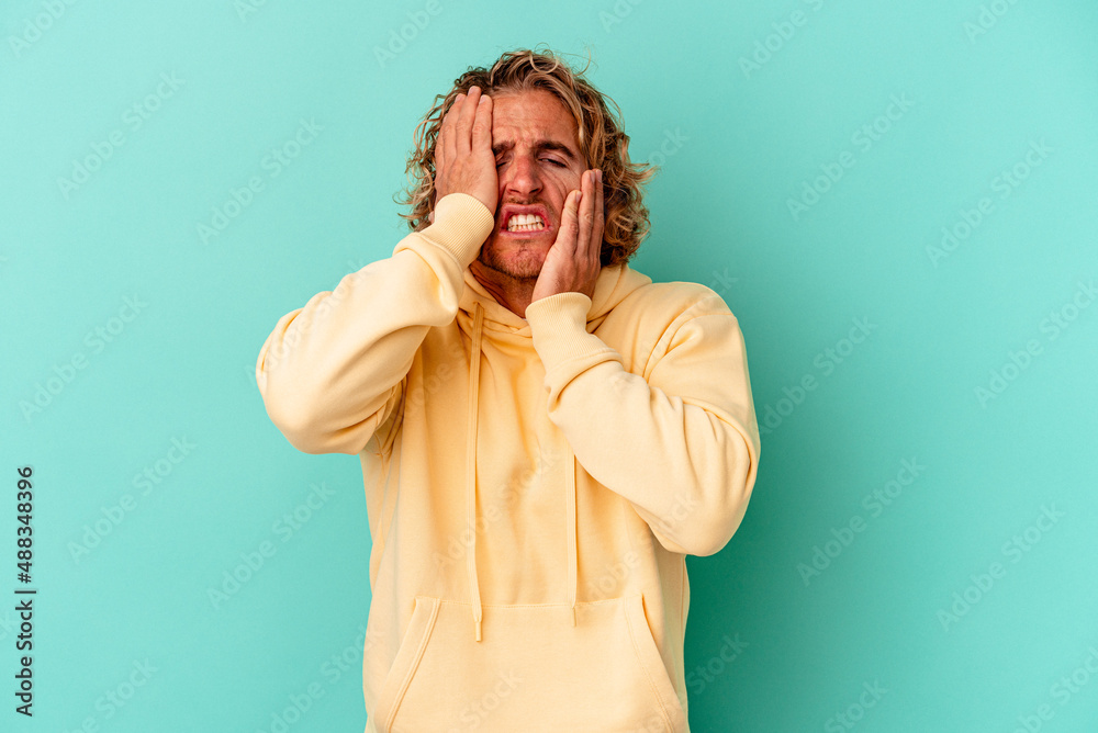 Young caucasian man isolated on blue background crying, unhappy with something, agony and confusion concept. Young caucasian man isolated on blue background crying, unhappy with something, agony and confusion concept.
