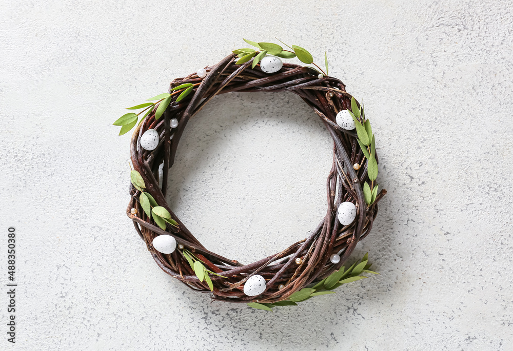 Beautiful Easter wreath with eggs and green branches on light background Beautiful Easter wreath with eggs and green branches on light background