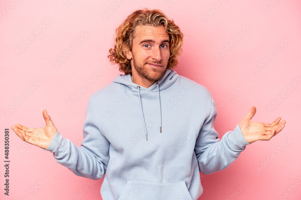 Young caucasian man isolated on pink background doubting and shrugging shoulders in questioning gesture. Young caucasian man isolated on pink background doubting and shrugging shoulders in questioning gesture.