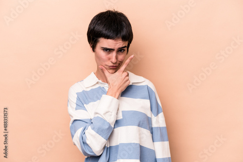 Young caucasian woman isolated on beige background contemplating, planning a strategy, thinking about the way of a business.