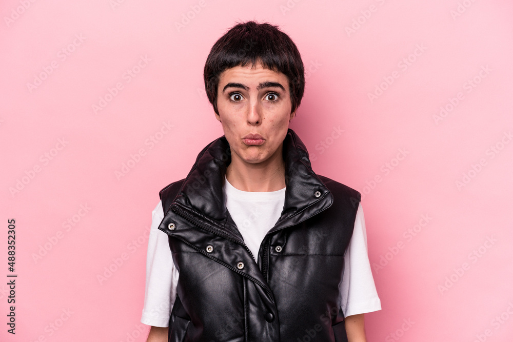 Young caucasian woman isolated on pink background blows cheeks, has tired expression. Facial expression concept. Young caucasian woman isolated on pink background blows cheeks, has tired expression. Facial expression concept.