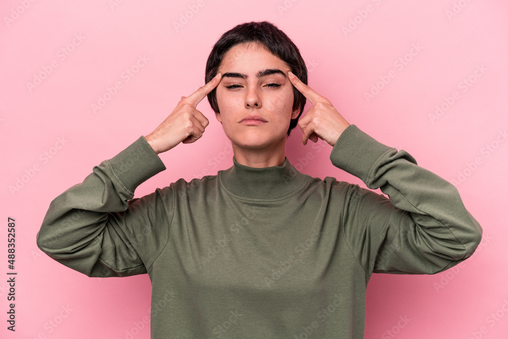 Young caucasian woman isolated on pink background focused on a task, keeping forefingers pointing head. Young caucasian woman isolated on pink background focused on a task, keeping forefingers pointing head.