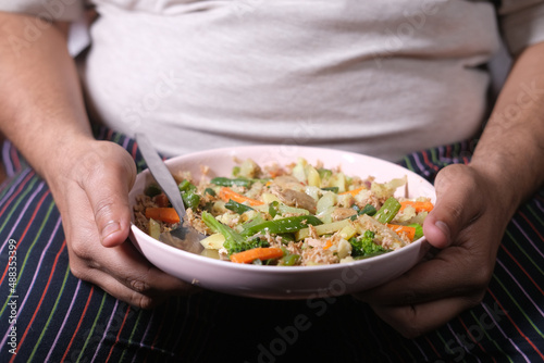  a fat men in casual dress eating fresh salad , healthy food concept 