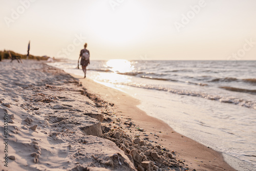 Evening walk along seashore or ocean against sun