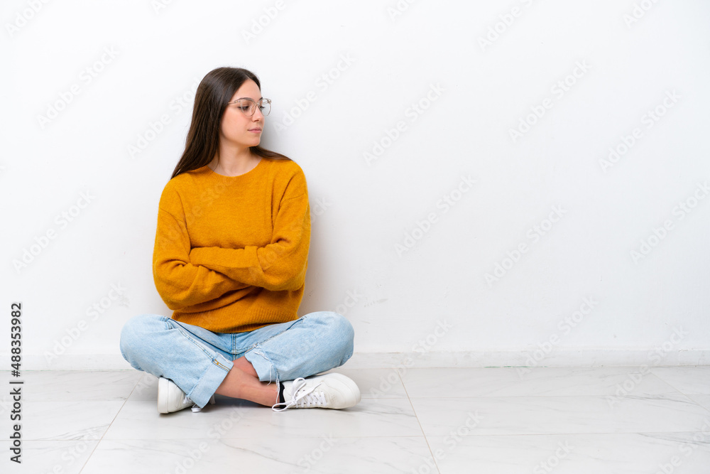 Young girl sitting on the floor isolated on white background in lateral position Young girl sitting on the floor isolated on white background in lateral position