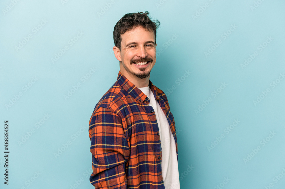 Fototapeta premium Young caucasian man isolated on blue background confident keeping hands on hips.