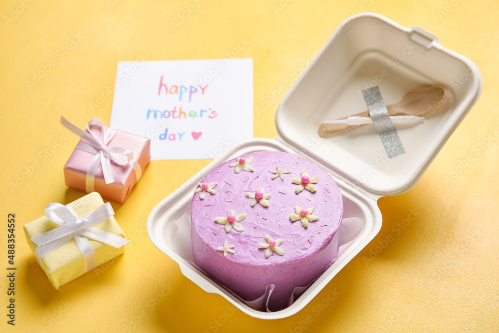 Plastic lunch box with tasty bento cake, greeting card and gifts on orange background Plastic lunch box with tasty bento cake, greeting card and gifts on orange background