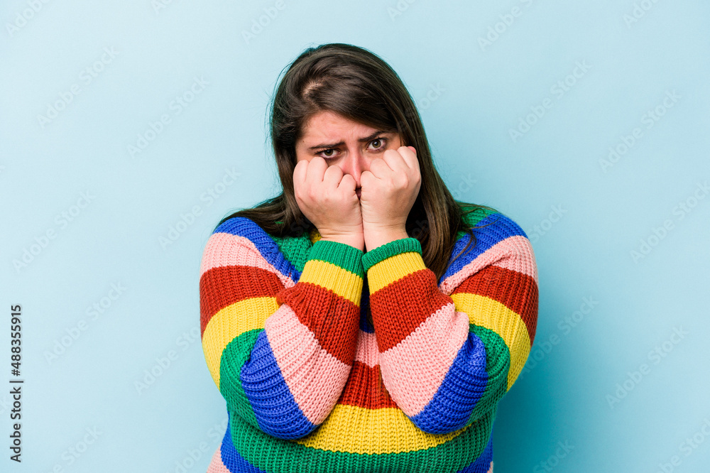 Young caucasian overweight woman isolated on blue background throwing a punch, anger, fighting due to an argument, boxing. Young caucasian overweight woman isolated on blue background throwing a punch, anger, fighting due to an argument, boxing.
