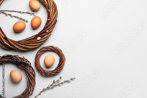 Nests with Easter eggs and willow branches on light background