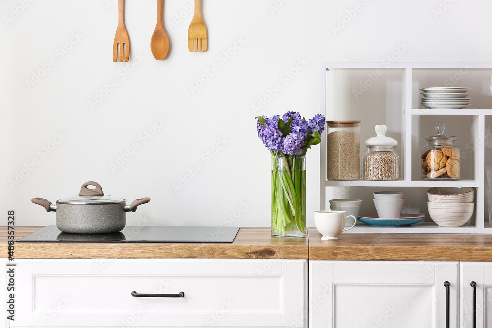 Vase with hyacinth flowers and cup of coffee on kitchen counter near white wall Vase with hyacinth flowers and cup of coffee on kitchen counter near white wall