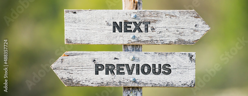 opposite signs on wooden signpost with the text quote next previous engraved. Web banner format. photo