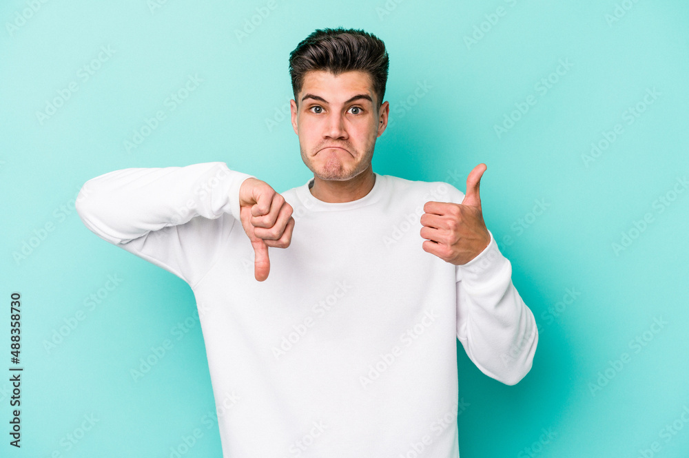 Young caucasian man isolated on blue background showing thumbs up and thumbs down, difficult choose concept Young caucasian man isolated on blue background showing thumbs up and thumbs down, difficult choose concept