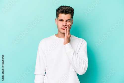 Young caucasian man isolated on blue background having a strong teeth pain, molar ache.