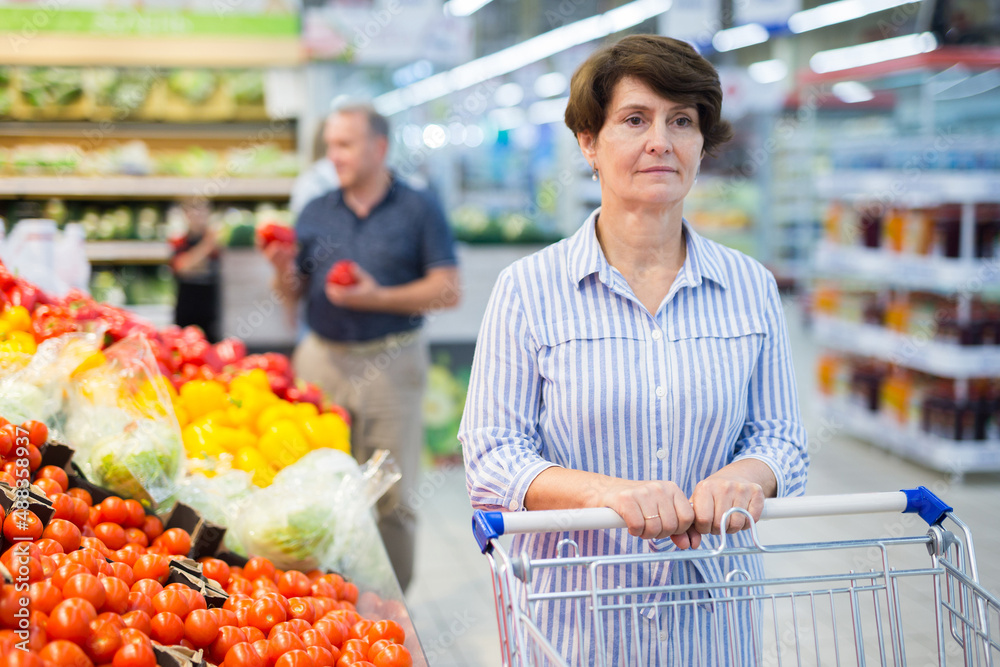 Mature woman choosing tomatoes in supermarket