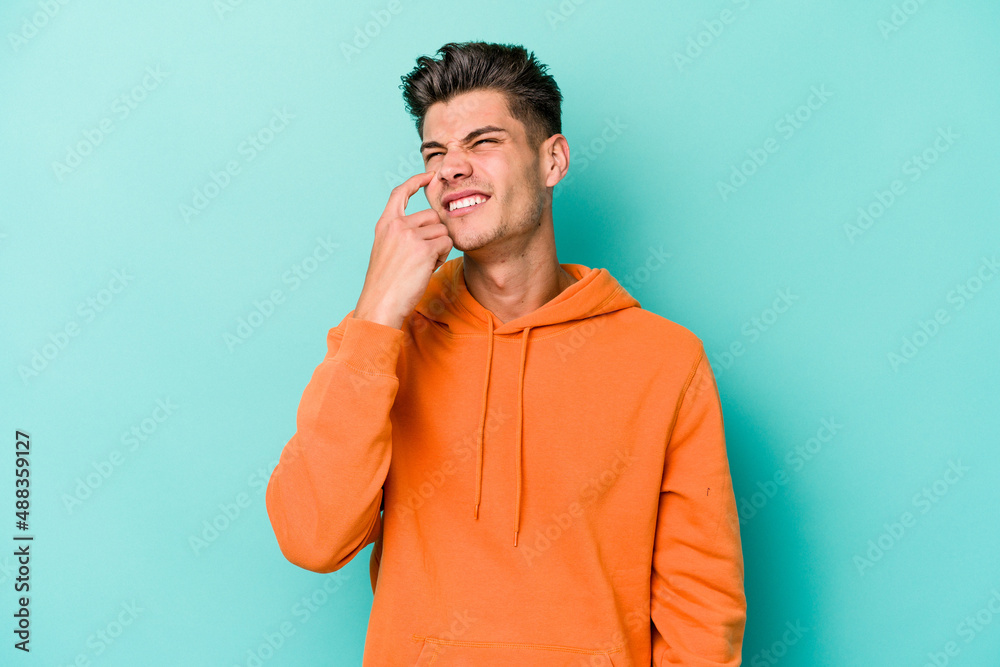 Young caucasian man isolated on blue background crying, unhappy with something, agony and confusion concept. Young caucasian man isolated on blue background crying, unhappy with something, agony and confusion concept.