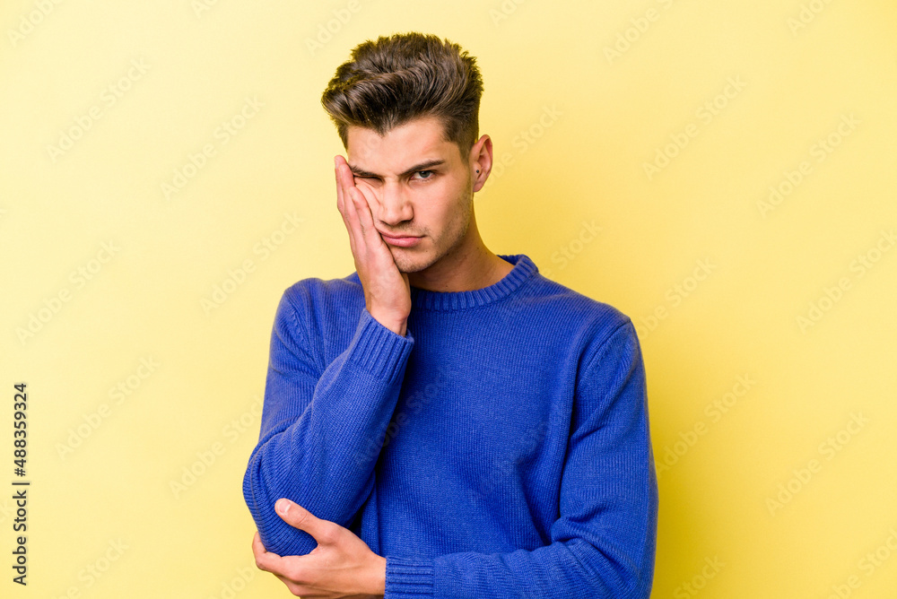 Young caucasian man isolated on yellow background who is bored, fatigued and need a relax day. Young caucasian man isolated on yellow background who is bored, fatigued and need a relax day.