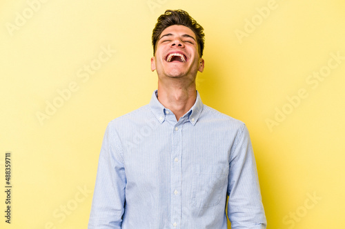 Young caucasian man isolated on yellow background relaxed and happy laughing, neck stretched showing teeth.