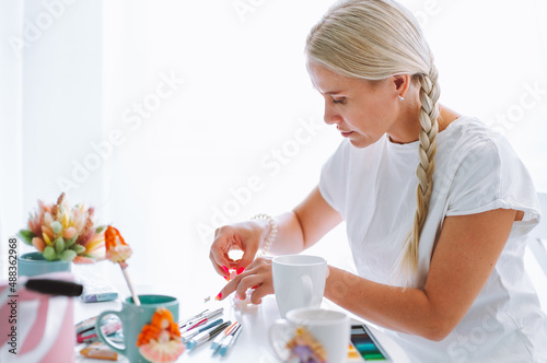Foto Portrait of woman artist jobbing and making decoration crafts colorful flowers on mugs of polymer clay