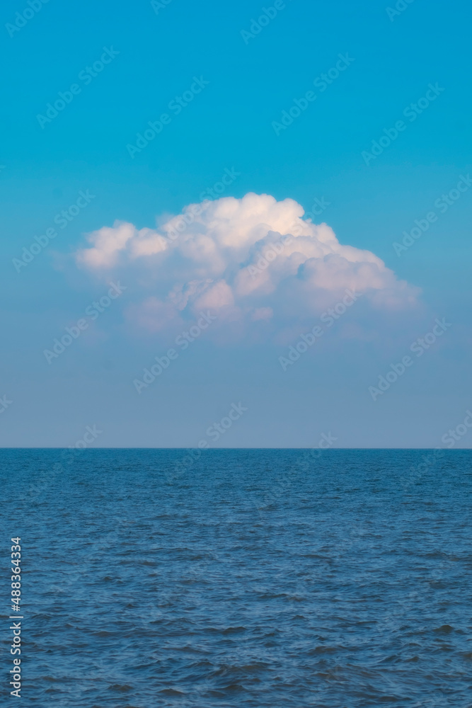 Blue Sea Ocean under blue sky with fluffy white cloud seascape nature background summer travel vacation vertical image