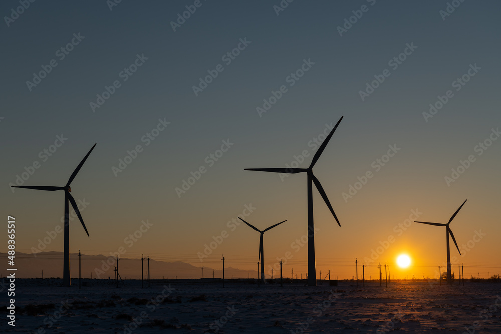 Wind turbines and power lines at sunset