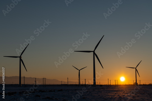 Wind turbines and power lines at sunset
