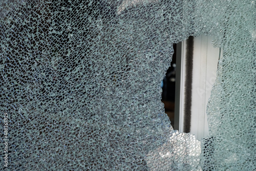 Cracked tempered glass with cracks pattern. Vandalism, destruction concept. Broken glass due to crime, robbery of shop concept.