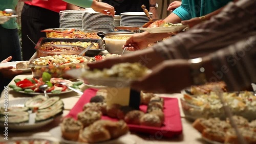 people picking food from a variety of dishes at a potluck table photo