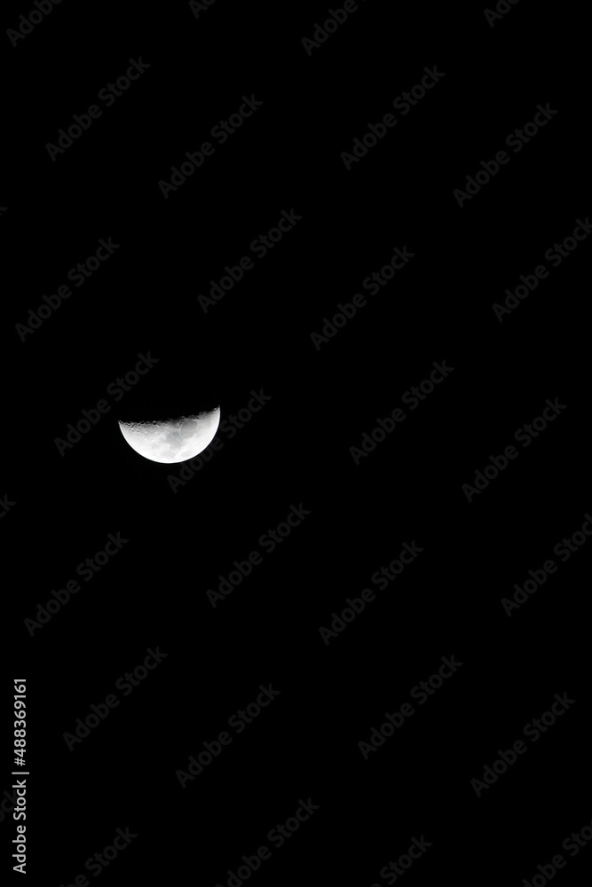 half moon. the moon is not full on an isolated dark background. Moon is an astronomical body that orbits planet Earth, being Earth's only permanent natural satellite. half moon. the moon is not full on an isolated dark background. Moon is an astronomical body that orbits planet Earth, being Earth's only permanent natural satellite.