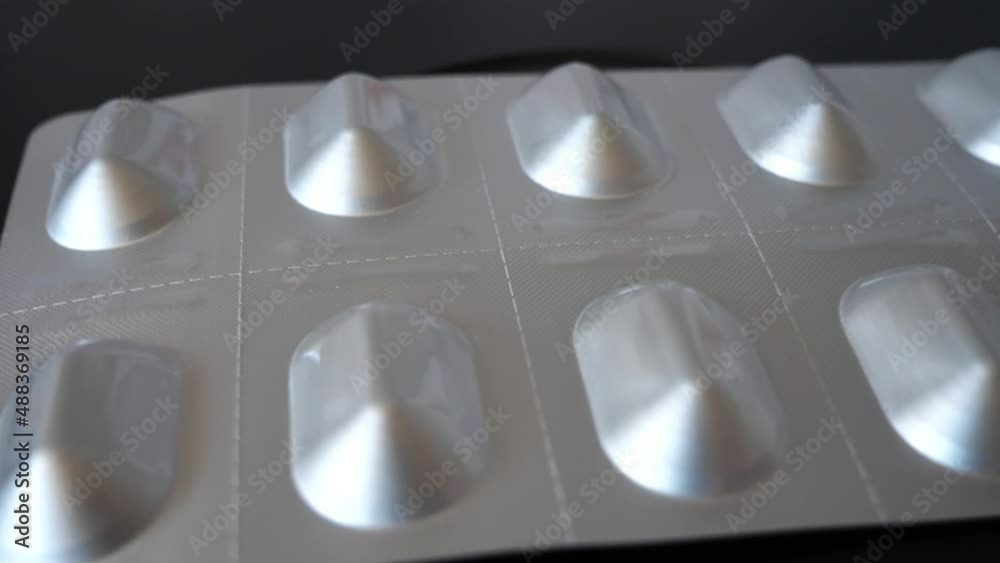 Packaging with pills on a black surface close-up. Pills macro.
Packaging with pills on a black surface close-up. Pills macro.
