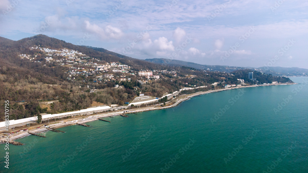 Aerial view of the southern city along the seashore. Road and railway along the sea line. Russia, Sochi, Red Storm.