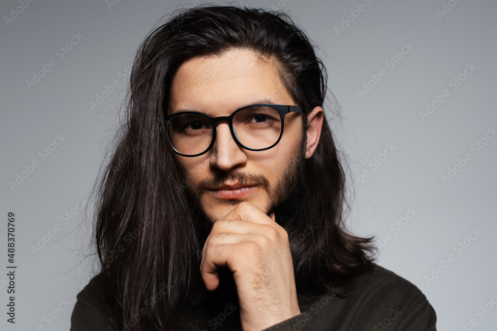 Portrait of young handsome man with expressive face and long hair, wearing glasses. Portrait of young handsome man with expressive face and long hair, wearing glasses.