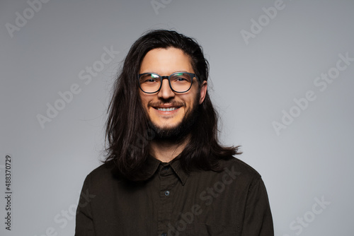 Portrait of young smiling handsome man with long hair and glasses.