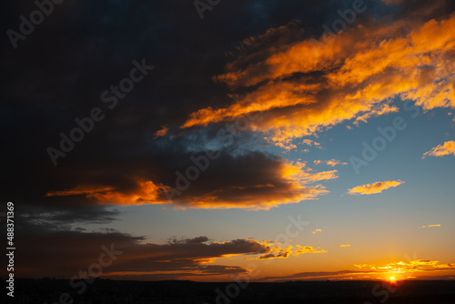 Natural landscape. Reflection of sunset colourful light on dark cloudy sky.
