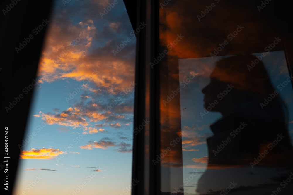 Blurred silhouette of girl through glass of window on background of sunset sky. Blurred silhouette of girl through glass of window on background of sunset sky.