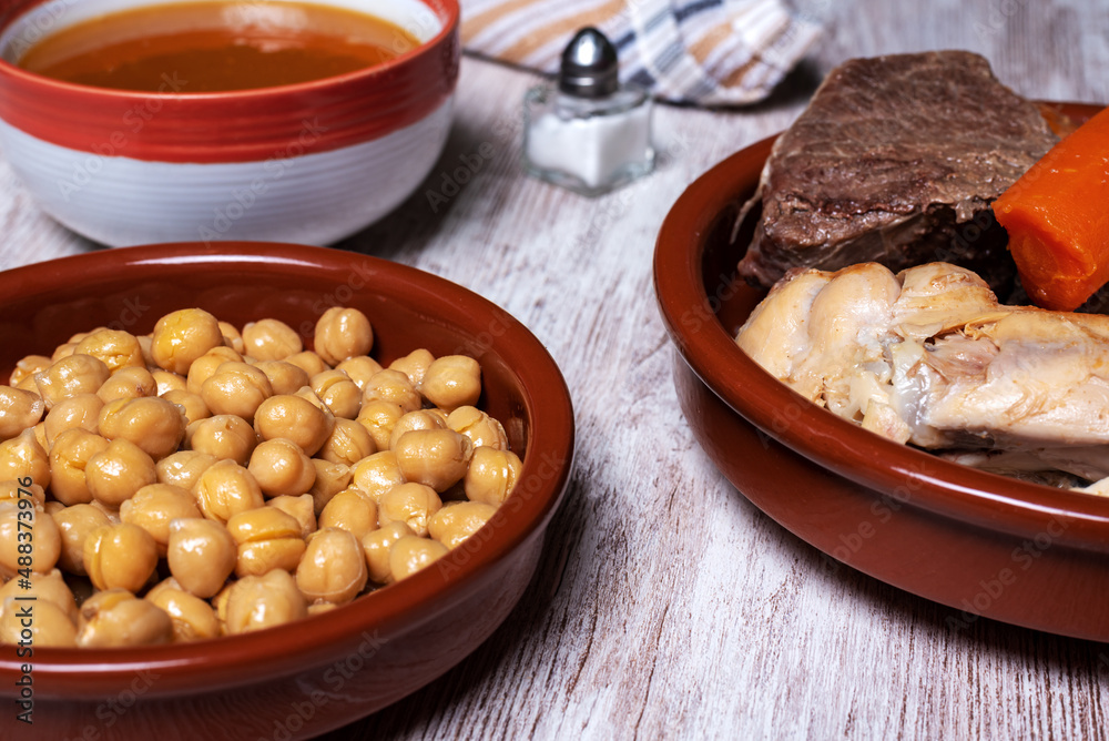 Cocido Madrileño, stew of chickpeas, vegetables, beef, chicken, chorizo and bacon typical of Madrid, served in separate dishes, soup, chickpeas and meat.