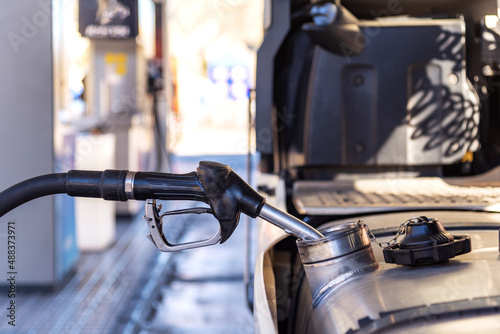 Truck refueling diesel at a highway gas station, close-up of the nozzle inserted in the vehicle's tank. photo