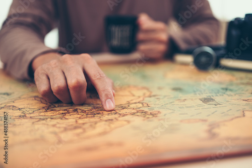 Tourist planning vacation, holiday with the help world map. Man's hand marks route on map and using pins and rope. Travel concept.