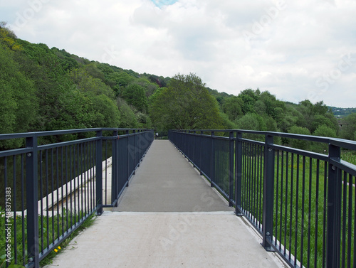 raised pedestrian footbridge over the brearley fields canal spillway next to the river calder in west yorkshire