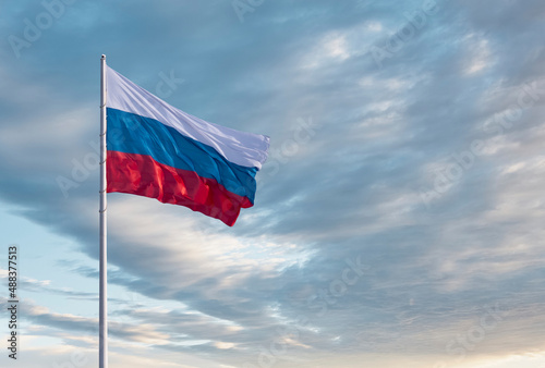 Waving Russian flag against a blue sky with clouds and empty space for text. Room for text. National flag of the Russian Federation. © Алексей Игнатов