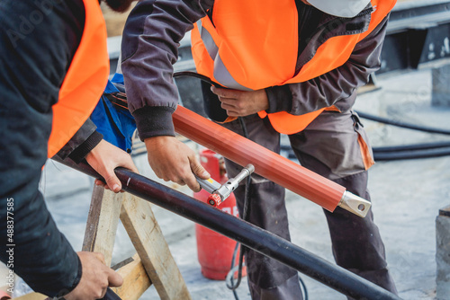 Two electrician builder workers installing high-voltage cable