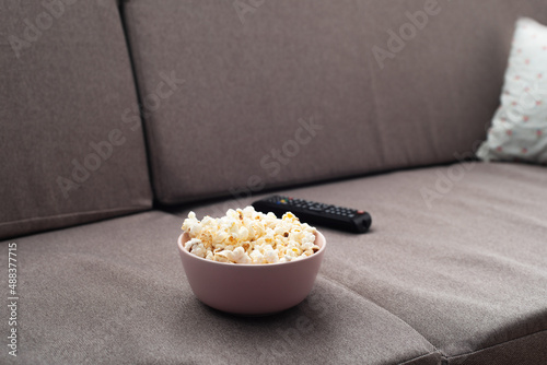 Obraz na płótnie Bowl with popcorn and tv remote control on sofa w salonie